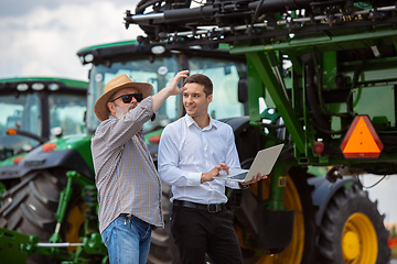 Image showing A farmer with a tractor, combine at a field in sunlight. Confident, bright colors