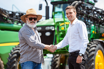 Image showing A farmer with a tractor, combine at a field in sunlight. Confident, bright colors