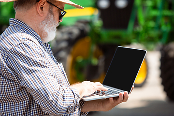 Image showing A farmer with a tractor, combine at a field in sunlight. Confident, bright colors