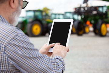 Image showing A farmer with a tractor, combine at a field in sunlight. Confident, bright colors