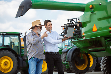 Image showing A farmer with a tractor, combine at a field in sunlight. Confident, bright colors