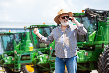 Image showing A farmer with a tractor, combine at a field in sunlight. Confident, bright colors