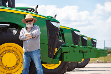 Image showing A farmer with a tractor, combine at a field in sunlight. Confident, bright colors