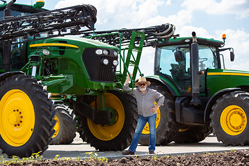 Image showing A farmer with a tractor, combine at a field in sunlight. Confident, bright colors