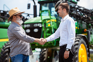 Image showing A farmer with a tractor, combine at a field in sunlight. Confident, bright colors