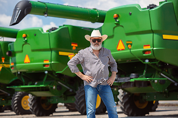 Image showing A farmer with a tractor, combine at a field in sunlight. Confident, bright colors