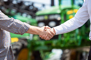 Image showing A farmer with a tractor, combine at a field in sunlight. Confident, bright colors