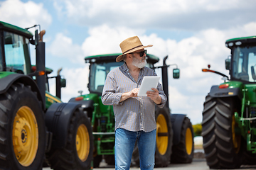 Image showing A farmer with a tractor, combine at a field in sunlight. Confident, bright colors