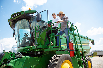 Image showing A farmer with a tractor, combine at a field in sunlight. Confident, bright colors