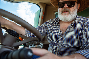 Image showing A farmer with a tractor, combine at a field in sunlight. Confident, bright colors