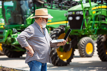 Image showing A farmer with a tractor, combine at a field in sunlight. Confident, bright colors