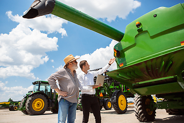 Image showing A farmer with a tractor, combine at a field in sunlight. Confident, bright colors