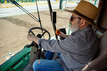 Image showing A farmer with a tractor, combine at a field in sunlight. Confident, bright colors