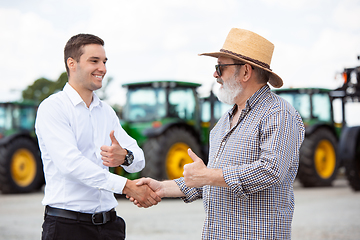 Image showing A farmer with a tractor, combine at a field in sunlight. Confident, bright colors