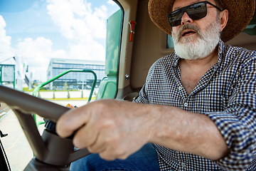 Image showing A farmer with a tractor, combine at a field in sunlight. Confident, bright colors