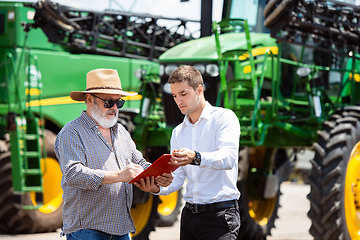 Image showing A farmer with a tractor, combine at a field in sunlight. Confident, bright colors