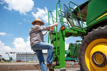 Image showing A farmer with a tractor, combine at a field in sunlight. Confident, bright colors