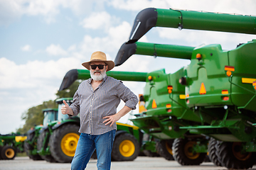 Image showing A farmer with a tractor, combine at a field in sunlight. Confident, bright colors