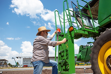 Image showing A farmer with a tractor, combine at a field in sunlight. Confident, bright colors