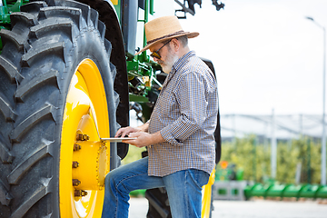 Image showing A farmer with a tractor, combine at a field in sunlight. Confident, bright colors