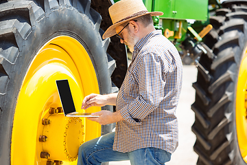 Image showing A farmer with a tractor, combine at a field in sunlight. Confident, bright colors