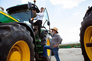 Image showing A farmer with a tractor, combine at a field in sunlight. Confident, bright colors