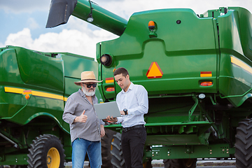 Image showing A farmer with a tractor, combine at a field in sunlight. Confident, bright colors