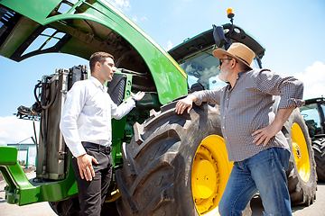 Image showing A farmer with a tractor, combine at a field in sunlight. Confident, bright colors