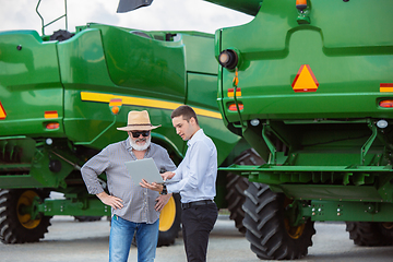 Image showing A farmer with a tractor, combine at a field in sunlight. Confident, bright colors