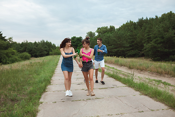 Image showing Group of friends clinking beer bottles during picnic in summer forest. Lifestyle, friendship