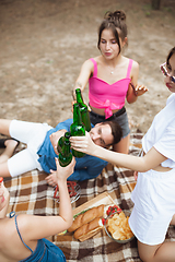 Image showing Group of friends clinking beer bottles during picnic in summer forest. Lifestyle, friendship