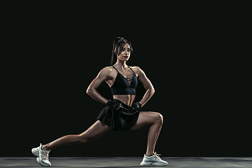 Image showing Beautiful young female athlete practicing on black studio background, full length portrait