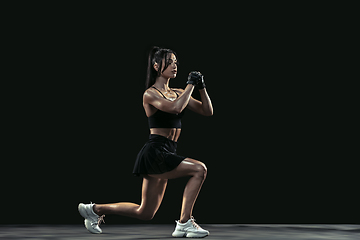 Image showing Beautiful young female athlete practicing on black studio background, full length portrait