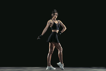 Image showing Beautiful young female athlete practicing on black studio background, full length portrait