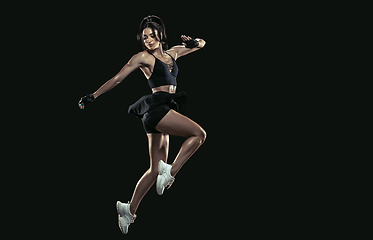 Image showing Beautiful young female athlete practicing on black studio background, full length portrait