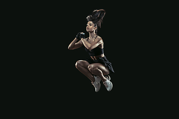 Image showing Beautiful young female athlete practicing on black studio background, full length portrait