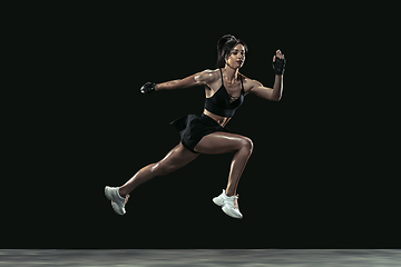 Image showing Beautiful young female athlete practicing on black studio background, full length portrait