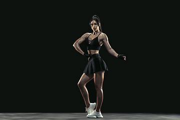 Image showing Beautiful young female athlete practicing on black studio background, full length portrait