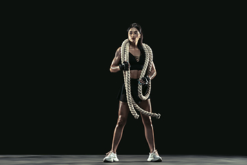 Image showing Beautiful young female athlete practicing on black studio background, full length portrait