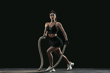 Image showing Beautiful young female athlete practicing on black studio background, full length portrait