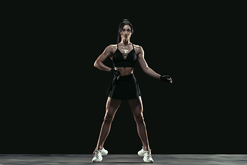 Image showing Beautiful young female athlete practicing on black studio background, full length portrait