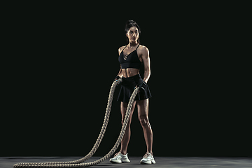 Image showing Beautiful young female athlete practicing on black studio background, full length portrait