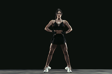 Image showing Beautiful young female athlete practicing on black studio background, full length portrait