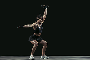 Image showing Beautiful young female athlete practicing on black studio background, full length portrait