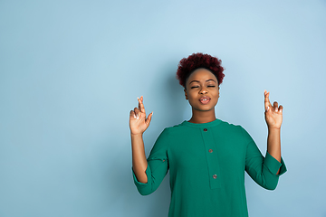 Image showing African-american beautiful young woman\'s portrait on blue studio background, emotional and expressive. Copyspace for ad.