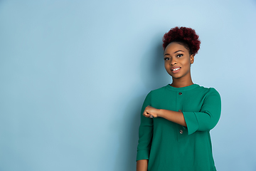 Image showing African-american beautiful young woman\'s portrait on blue studio background, emotional and expressive. Copyspace for ad.