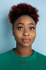 Image showing African-american beautiful young woman\'s close up portrait on blue studio background, emotional and expressive. Copyspace for ad.