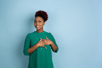 Image showing African-american beautiful young woman\'s portrait on blue studio background, emotional and expressive. Copyspace for ad.