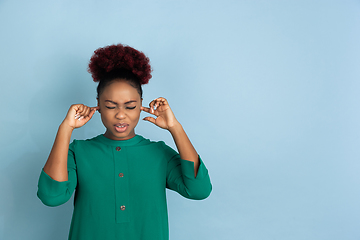 Image showing African-american beautiful young woman\'s portrait on blue studio background, emotional and expressive. Copyspace for ad.