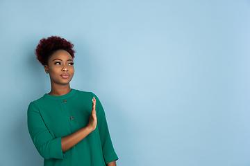 Image showing African-american beautiful young woman\'s portrait on blue studio background, emotional and expressive. Copyspace for ad.